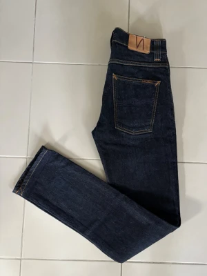 Nudie Jeans - Oerhört feta Nudie Jeans i toppskick! Stilrena detaljer som matchar bra med den mörkblåa färgen. Inga defekter och otroligt sköna att ha på sig! Längd - 107 och bredd - 39 cm. 