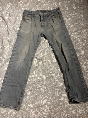 Ljusgrå raka jeans från Dressmann - Säljer ett par ljusgrå jeans från Dressmann i rak modell. Jeansen har klassisk femficksdesign och är tillverkade i ett mjukt denimtyg. Perfekta för en avslappnad och stilren look.