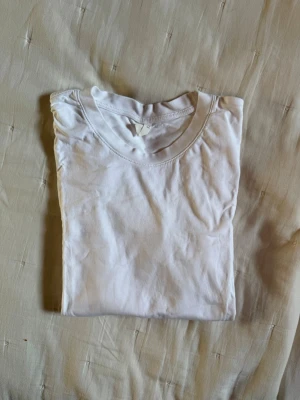 Vit basic t-shirt i bomull - En klassisk vit t-shirt från ARKET med rund halsringning i mjuk bomull. Perfekt att styla till jeans eller shorts för en clean och enkel look. T-shirten har korta ärmar och en normal passform.