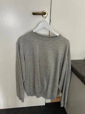 Grå sweatshirt från Weekday - En enkel och stilren grå sweatshirt från Weekday. Tröjan har rund halsringning, ribbade muddar vid ärmslut och nederkant samt en avslappnad passform. Perfekt för en casual look och lätt att matcha med jeans eller byxor.