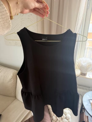 Svart ärmlös topp från Gina Tricot - Säljer en svart ärmlös topp från Gina Tricot med rund halsringning och volangdetalj nedtill. Toppen har en enkel och stilren design som passar perfekt till jeans eller kjol.🖤