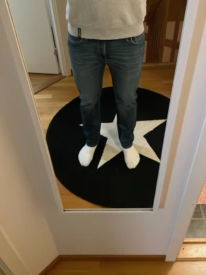 Jack and Jones jeans - Säljer ett par mörkblå jeans med raka ben och klassisk femficksmodell. Jeansen har diskreta slitningar framtill och är tillverkade i ett mjukt denimtyg som sitter skönt. Perfekta till vardags för en avslappnad look.