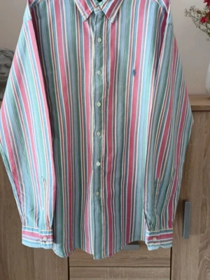 Ralph Lauren skjorta - Riktigt snygg Ralph Lauren-skjorta med klassiskt färgstarkt randmönster. Button-down-krage och ikoniska Polo-loggan på bröstet.
