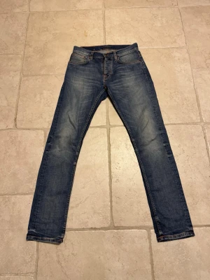 Blå slim fit jeans med slitningar - Snygga blå Nudie slim fit jeans med lätt slitna detaljer och klassisk femficksdesign. Jeansen är knappast använda då jag beställde fel och glömde skicka tillbaka och tiden är ute för de så nu säljs dem här för ett bra pris jag säljer de för 849 och de köptes för ungefär 3-4 veckor sen för 1799kr så dessa jeans är perfekt för dig som vill ha ett par riktigt snygga jeans men inte lägga för mycket pengar! Kan gå ner till runt 700 vid snabb affär!