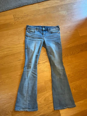 Blå low rise flare jeans, storlek 29 - Snygga blå jeans med låg midja och utsvängda ben, så kallad flare-modell. Klassisk femficksdesign och ljus tvätt. Perfekta för dig som gillar retrovibbar och vill ha ett par jeans som sticker ut lite extra.