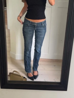 Blå low waist bootcut jeans - Säljer ett par blå low waist jeans med bootcut passform och slitningar framtill. Jeansen är vintage och så coola💙 