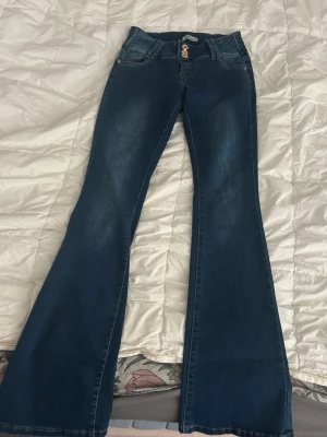 Mörkblå bootcut jeans - Snygga mörkblå lågmidjade bootcut jeans med söta detaljer på fickorna. Jeansen är väldigt stretchiga och små i storleken, därav är det en L men passar xs-m skulle jag säga. Använda 1-2 gånger💞💞