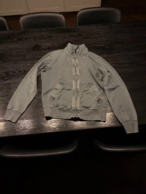 Grå Stone Island Zip-up - Snygg grå zip-up från Stone Island med hög krage och dragkedja framtill. Saknar badgen men kan lätt bytas ut.