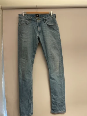 Ljusblå raka jeans från Lee - Säljer ett par ljusblå jeans från Lee med klassisk femficksdesign och raka ben. Jeansen har normal midja och är tillverkade i ett mjukt denimtyg. Perfekta för en avslappnad och stilren look.