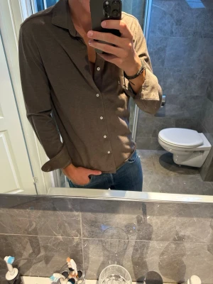 Brun långärmad skjorta i bomull - Riktigt schysst brun skjorta från märket bläck.passar perfekt nu till hösten. Jag på bilden är 188cm och bär strlk M. I övrigt superbra skick. Hör av er vid fler frågor;)