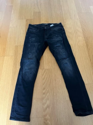 Jack and Jones slim Glenn  - Svarta Jack and Jones jeans med slitningar i modellen slim Glenn. Jeansen är i storlek W31 L30, och i mycket bra skick, finns inga tecken på användning.  Hör av er vid funderingar.