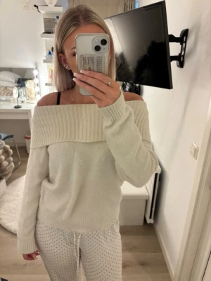 Off shoulder stickad tröja Lindex - Krämvit stickad off shoulder-tröja från Lindex med bred ribbad kant upptill. Mjuk och fluffig känsla, perfekt för dig som gillar en avslappnad men ändå trendig look. Långa ärmar och ribbade muddar vid ärmslut och nederkant. Tröjan är lite nopprig och kan ha fläckar men går säkert bort om man försöker 