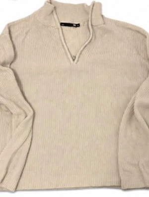 Beige ribbstickad tröja med krage - Beige ribbstickad tröja med halvkrage och v-ringad öppning framtill. Tröjan har långa ärmar och är tillverkad i ett mjukt, tjockare material som passar perfekt för kyligare dagar. Enkel och stilren design som är lätt att matcha.
