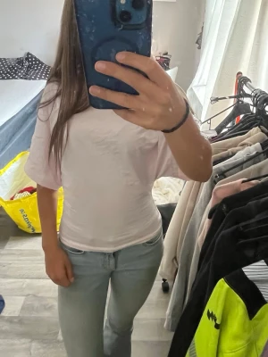 Ljus rosa kortärmad t-shirt i bomull från Nelly - En enkel och stilren rosa t-shirt med korta ärmar och rund hals. T-shirten har en normal passform och är gjord i mjuk bomull, perfekt till jeans eller shorts för en clean look. T shortsen är sydd för att vara större vid armarna och smalare vid midjan för en snyggare look