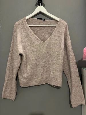 Rosa-Beige v-rongad stickad tröja - Mysig rosa-beige stickad tröja med.            v-ringning och långa ärmar. Passformen är avslappnad. Perfekt för kyligare höst eller vinterdagar och enkel att styla. Pris går att diskuteras! Önskas fler bilder/mått är det bara att skriva!