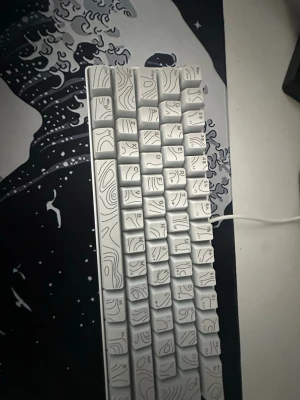 Vit tangentbord med mönstrade keycaps. Olika RGB färger finns - Unikt vitt tangentbord med specialdesignade keycaps som har svarta linjemönster inspirerade av topografiska kartor. Tangentbordet är kompakt och ansluts med kabel. Perfekt för dig som vill ha en snygg och personlig setup.. PRIS KAN DISKUSERAS 🙏🙏