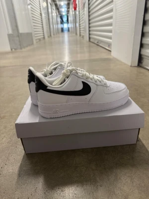 Nike Air Force 1 '07 Vita/Svarta Sneakers, strl 40. - Helt nya oanvända Nike Air Force 1 '07 Vita/Svarta Sneakers, strl 40.  Skorna har inte blivit använda eller testade. Original kartong medföljer  Nypris hos Nike 1400 kr.