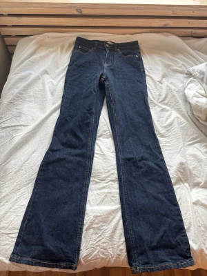 Mörkblå bootcut jeans - Snygga mörkblå bootcut jeans med klassisk femficksdesign och kontrastsömmar. Jeansen har normal midja och är tillverkade i ett mjukt denimtyg som ger en skön passform. Perfekta för dig som gillar en bekväm och fin stil. Aldrig använda. Nypris 500 kr, mitt pris 249 kr. 