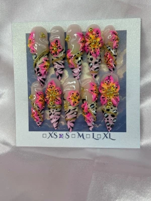 Frankie (S);ExtraLongStiletto  - Unika handgjorda press-on naglar i en extra lång stilettoform med handmålade neonrosa och gula blommor, svartvita tiger/zebramönster och gulddetaljer. Naglarna har en glansig finish och 3D-effekter som verkligen sticker ut. Perfekt för dig som vill ha något riktigt extra till naglarna. Inspo av konstnären Lisa Frank.S: 15 mm, 11,5 mm, 12 mm, 11 mm, 9 mm 