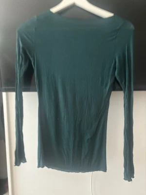 Mörkgrön långärmad topp Intimissimi - Säljer en mörkgrön långärmad topp från Intimissimi. Toppen är tight i modellen och tillverkad i ett mjukt material med inslag av kashmir, vilket gör den extra skön att ha på sig. Perfekt att styla med jeans eller kjol för en clean look.