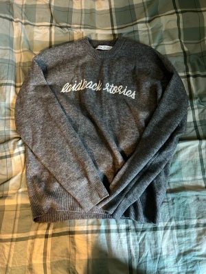 Grå sweatshirt med texttryck - Mysig grå sweatshirt med texten 'laidback stories' framtill och städer som New York, Paris, Stockholm och Madrid tryckta på ryggen. Tröjan har rund halsringning och ribbade muddar vid ärmslut och nederkant. Perfekt för en avslappnad stil.