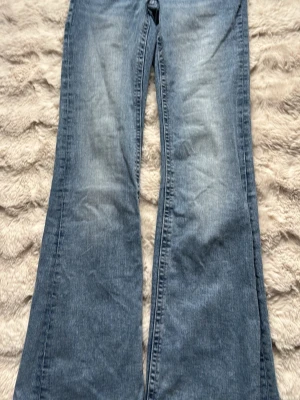 Blå bootcut jeans med broderade fickor - Säljer ett par ljusblå bootcut jeans med snyggt broderade bakfickor. Jeansen har en klassisk femficksmodell och är tillverkade i denim. Perfekta för dig som gillar en retro och avslappnad stil. Storlek 170 , pris 150kr