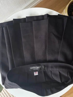 Ny American Apparel Svart Veckad Minikjol, storlek S - Oanvänd!  Strl.Small (midjemått 35 cm, mätt rakt över)  ”Klassisk plisserad kjol i svart. Kjolen har en tidlös design med veck som ger den volym och rörelse. Den är försedd med en knapp i midjan för enkel knäppning. Passar utmärkt för en mängd olika tillfällen, från vardagsbruk till mer uppklädda evenemang.”  Nypris 899kr  Se gärna mina övriga annonser för bundlerabatter och samfrakt!