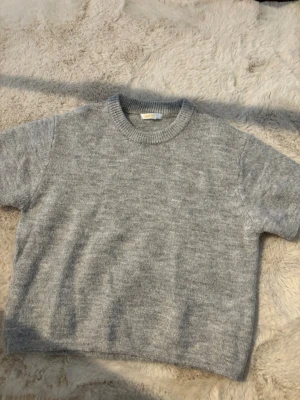 Ljusgrå stickad tröja - Mysig ljusgrå stickad tröja med rund halsringning. Perfekt för kyliga dagar och enkel att matcha med olika outfits.