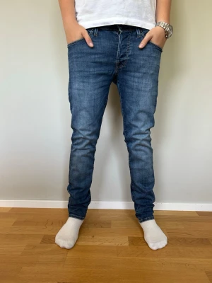 Blå slim fit jeans herr Glenn Jack and Jones  - Snygga blå slim fit jeans från Jack and Jones. Jeansen har en lätt tvättad look och smal passform som sitter tajt längs benen. Perfekta för en avslappnad och trendig stil. Materialet är troligtvis bomull med stretch för extra komfort. Jeansmodell Glenn slim W29 L30. Pris kan diskuteras vid smidig affär.