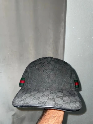 Svart Gucci keps med GG-mönster - Snygg svart keps från Gucci storlek L 59cm. Pris går att diskuteras, endast seriösa köpare. Äkta såklart.