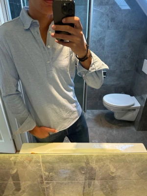 Ljusblå långärmad piké  - Säljer en stilren ljusblå piké från John Henric. Riktigt bra skick och inga defekter eller tecken på användning. Jag på bilden är 188cm och bär strlk M. Hör av er vid fler frågor:)