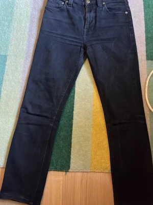 Mörkblå raka jeans - Snygga svarta jeans med rak passform och klassisk femficksdesign. Jeansen har normal midja och stängs med knapp och dragkedja. Materialet ser ut att vara denim med en mjuk finish. Perfekta för en avslappnad och stilren look.