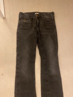 Svarta jeans med silver och guld detaljer  - Svarta jeans från Gina 