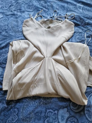 Beige långklänning med cut out - Trendig beige långklänning med tunna axelband och snygg cut out-detalj i midjan. Klänningen har en smickrande passform och är perfekt för sommarens alla tillfällen. Materialet är luftig och behagligt 🌸