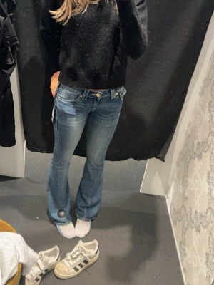 Blå bootcut jeans True Religion - Säljer ett par blå bootcut jeans från True Religion med snygga kontrastsömmar i en gul färg. Dem är i mycket bra skick och nypriset är 1399kr🥰 Det är storlek 25 i modellen Joey❤️