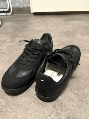 Svarta Margielas - Stilrena margielas i mocka och läder. Snygg och enkel design som passar till det mesta. Insidan är ljus och sulan är svart. Har tyvärr inte kvar skokartongen men har orginal påsen till skorna. Skicka gärna vid intresse eller frågor.