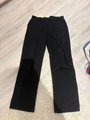Svarta mjukisbyxor med raka ben - Ett par svarta mjukisbyxor med raka ben och dragsko i midjan. Byxorna har en enkel och clean look, perfekta för chill dagar. Tillverkade i mjukt material som känns skönt mot huden.