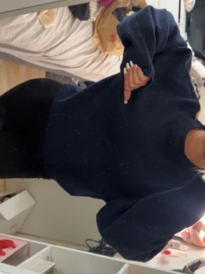 Mörkblå stickad tröja - Mysig mörkblå stickad tröja med oversized passform och rund halsringning. Tröjan har långa ärmar och ribbade muddar vid ärmenoch nederkant. Perfekt för lager på lager och en avslappnad look.