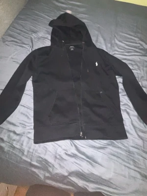 Svart hoodie från Polo Ralph Lauren - Säljer min zip hoodie svart Ralph lauren för ett bra pris, enda lilla felet är att ena snöret är trasigt annars så är hela hoodien jättefin med inga håll eller något, köpte den för ca 2300kr och mitt pris är 1399kr! Pris kan diskuteras på snabb affär.