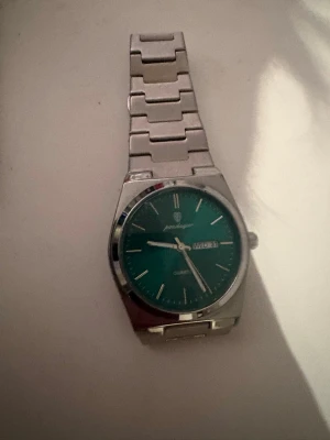 Poedagar Oak - 41 mm - Stilren klocka från Poedagar med grönt ur och dag/datumvisning. Armbandet är i metall med en klassisk länkdesign och boetten är rund. Perfekt accessoar för dig som gillar en tidlös look.