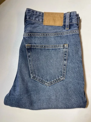 Blå raka jeans - Klassiska blå jeans i rak modell med hög midja och fem fickor. Jeansen har en ljus tvätt och är gjorda i kraftigt denimtyg. Passar perfekt till en avslappnad och trendig stil.