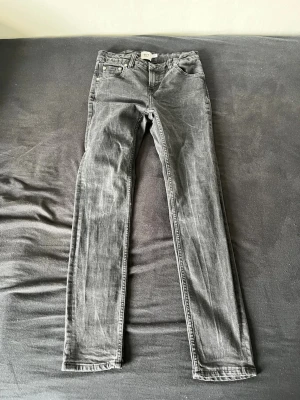 Grå slim fit jeans - Säljer ett par grå slim fit jeans med klassisk femficksdesign och dragkedjegylf. Jeansen har en tvättad look och raka ben. Perfekta för dig som gillar en avslappnad men ändå stilren stil.