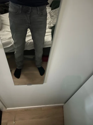 Grå slim fit jeans - Snygga grå slim fit jeans med klassisk femficksdesign och dragkedjegylf. Jeansen har en lätt tvättad look och smal passform som sitter tajt längs benen. Perfekta för en stilren och modern outfit. W28, L32
