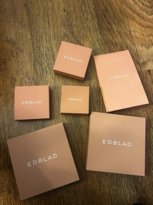 Beige askar från Edblad - Säljer flera stilrena askar från Edblad i beige färg med vit logga. Perfekta för att förvara smycken eller småsaker. Askarna är fyrkantiga och tillverkade i hård kartong med svart insida. 2 till halsband, 2 till armband 1 till ring och en påse