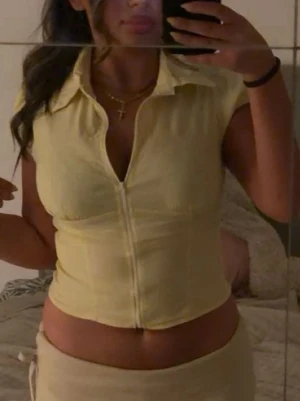 Gul croppad topp med dragkedja - Snygg ljusgul croppad topp med dragkedja framtill och krage. Toppen har korta ärmar och en figurnära passform som framhäver siluetten. Perfekt för dig som vill ha en trendig och fräsch look till sommaren. Från SHEIN.