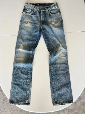 Blå slitna raka jeans från Nudie  - Säljer ett par blå jeans med slitningar från Nudie.       Lite baggy vilket görs et perfekt för en Street style eller bara en avslappnad stil.                                   Waist-30         Lenght-34