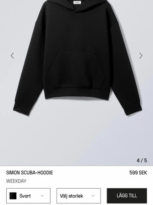 Svart hoodie från Weekday - En stilren svart hoodie från Weekday i modellen Simon Scuba. Hoodien har en rymlig huva, breda muddar och en stor känguruficka framtill. Tillverkad i ett tjockare, mjukt material som ger en clean och modern look.