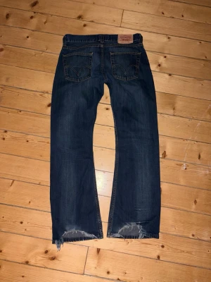 Mörkblå bootcut jeans med rå kant - Säljer ett par mörkblå bootcut jeans med rå, fransig kant nedtill. Myckey trendiga 512 bootcut som slutat tillverkas!