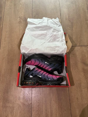 Helt nya Nike Air Max Plus TN (Rosa/Svart) - Strl 39 🔥✨ - Säljer ett par grymma och helt nya Nike Air Max Plus (TN) i en snygg färgövergång från rosa till svart. Skorna är aldrig använda, kommer med originalkartong och tagsen sitter kvar!  Storlek: 39  Skick: Helt nya / Deadstock (DS) i box  Färg: Black/Pink Gradient  Kvitto: Saknas Skickas spårbart eller hämtas enligt överenskommelse. Köparen står för frakten. Skriv ett DM om du har några frågor eller vill ha fler bilder! 👟💨 