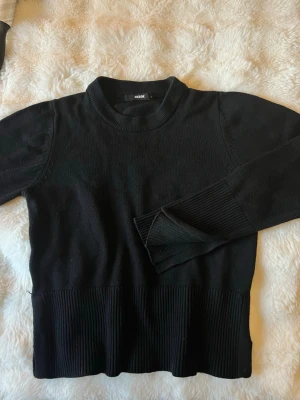 Svart stickad tröja  - Svart stickad tröja från Bik Bok med rund halsringning och breda ribbade muddar vid ärmslut och nederkant. Enkel och stilren design som passar perfekt till jeans eller kjol. Mjuk och skön att bära under kyliga dagar.
